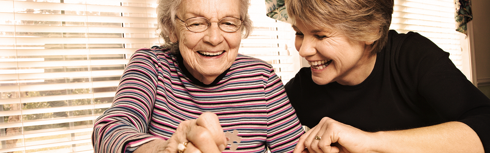 Young woman and older woman doing a puzzle Young woman and older woman doing a puzzle